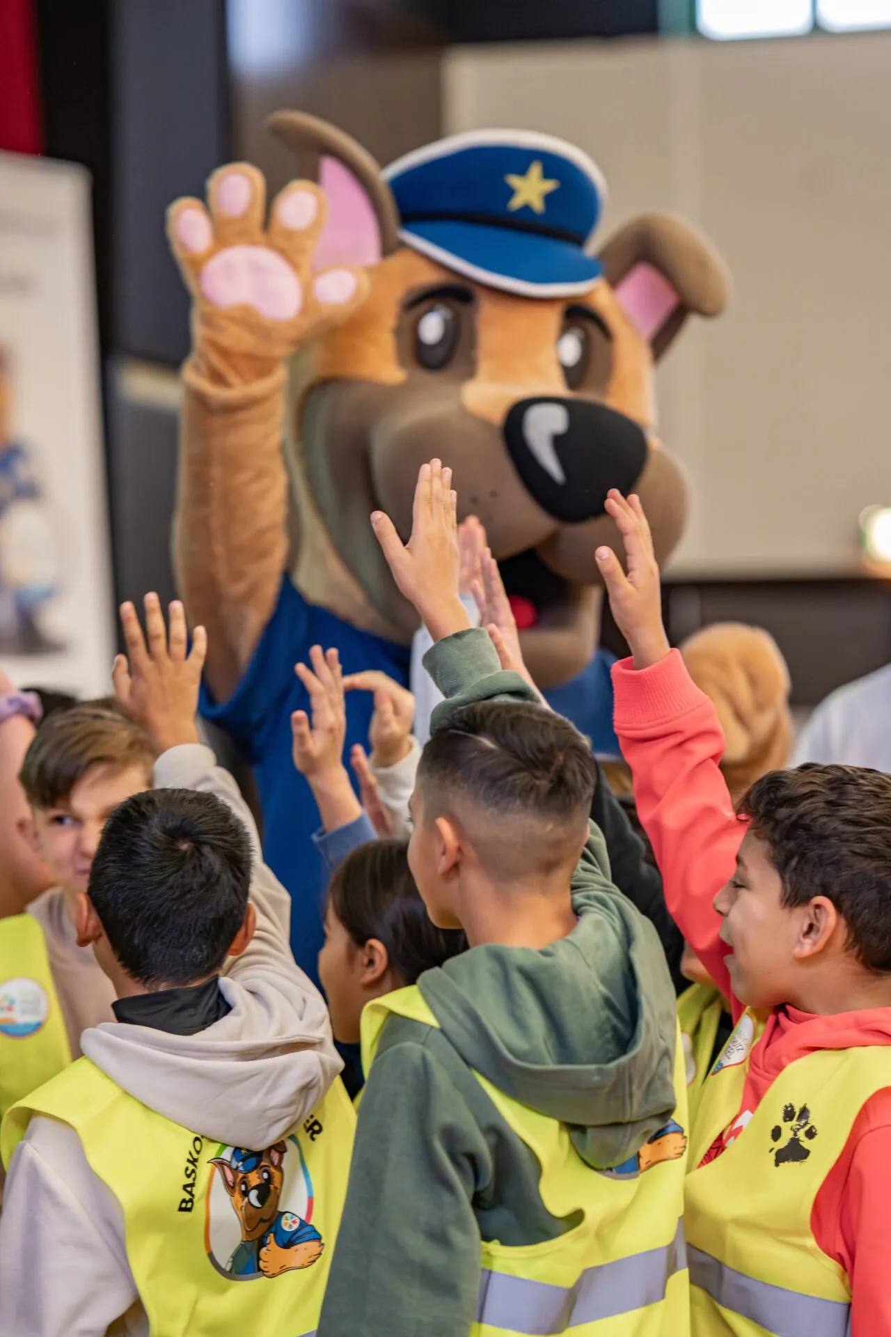 Basko im Kostüm gibt Kindern in gelben Warnwesten ein High Five