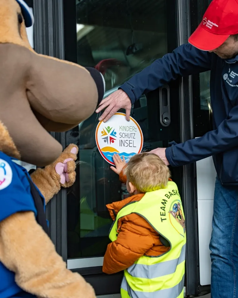 Basko bringt einen Aufkleber Kinder:Schutzinsel an