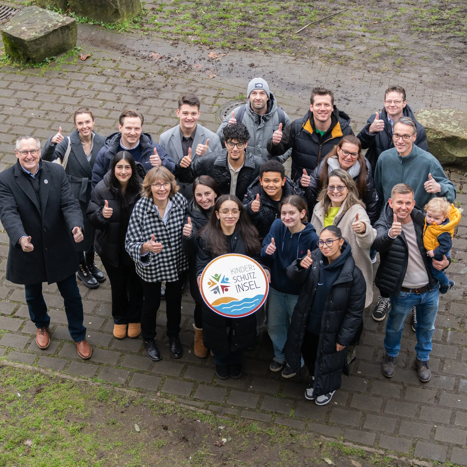 Große Gruppe von Kindern und Erwachsenen mit einem Schild Kinder:Schutzinsel