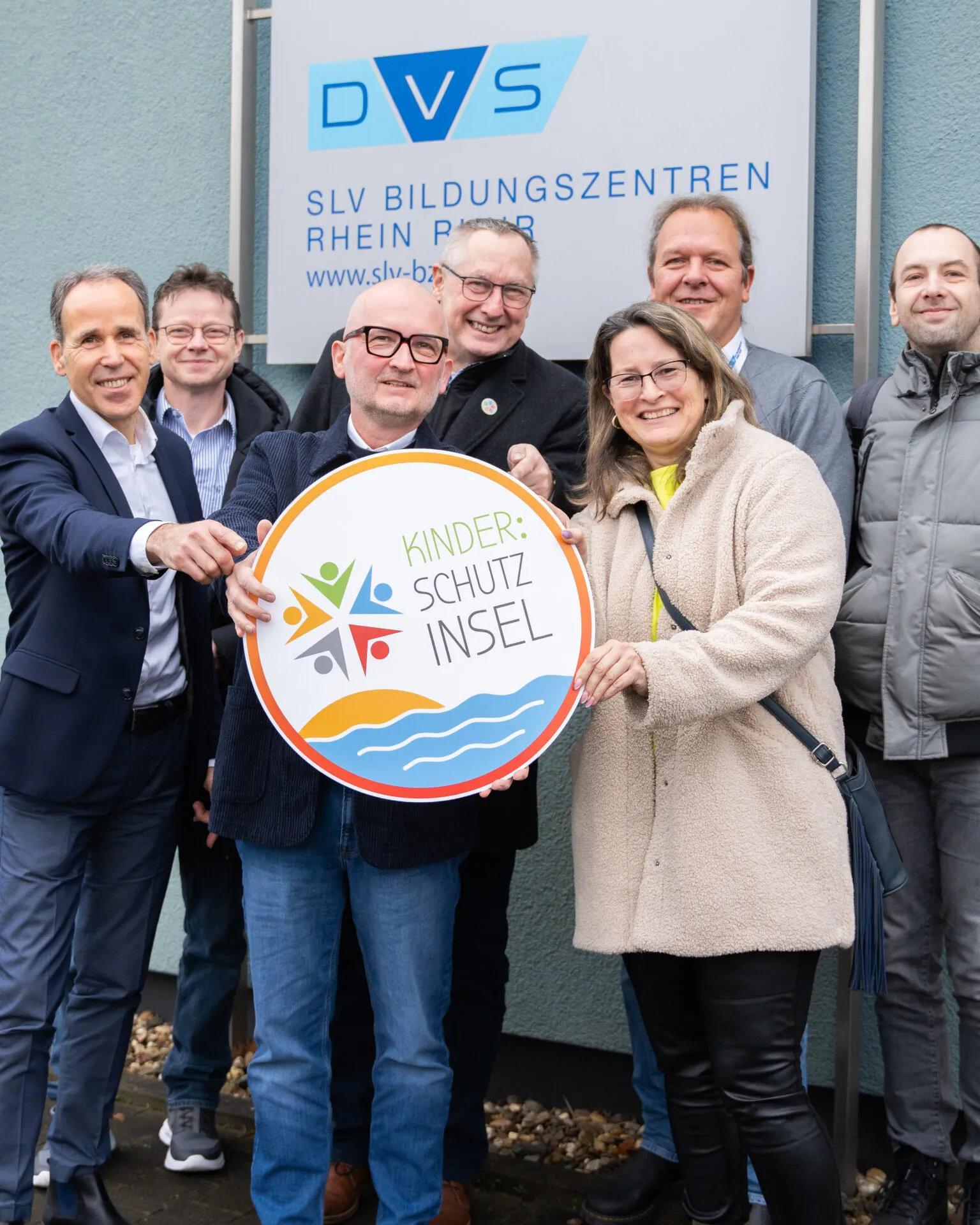 Partner halten das Schild Kinder:Schutzinsel