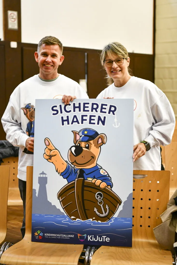 Zwei Multiplikator:innen halten das Plakat Sicherer Hafen